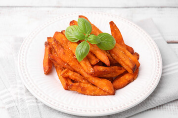 Sweet potato fries and basil on light wooden table, closeup