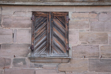 old wooden window with closed shutter in stone wall, no person