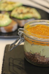 Layered Avocado and Marmalade Jar with Avocado Toast in Background