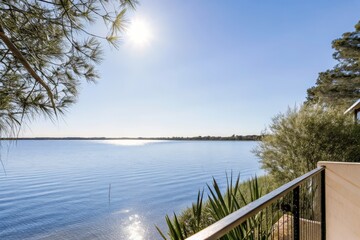 Peaceful sunny view over a calm lake with trees in the distance.