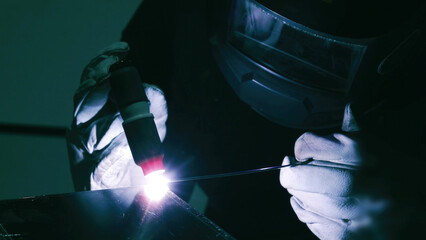 Skilled Welder Focused on Precision Metalwork with Bright Torch. A welder wearing protective gloves...