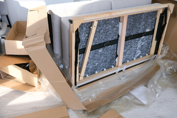 Unpacking a sofa during home renovation with cardboard and protective wrapping