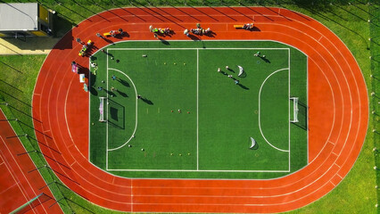 Aerial view of a vibrant sports field and running track. An overhead aerial view of a green sports...