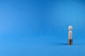 Wooden peg doll on stack of coins. Financial success concept. Copy space