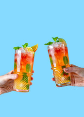 Strawberry mojito. Female hands holding two glasses with summer cocktails with ice and mint.