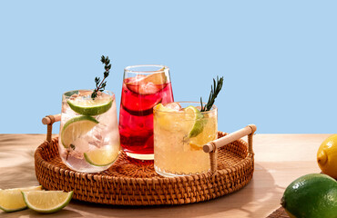 Sparkling cocktails with ice and citrus on a wicker tray. Popular bright refreshing alcohol drinks. Refreshing summer beverages.