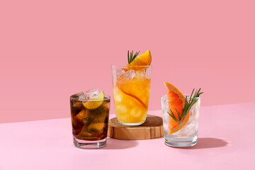 Cocktails with ice on a pink background. Set with different types of cocktails on a pink table. Whiskey with cola, Cuba Libre, gin and tonic with grapefruit and orange fresh.