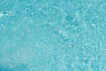 Blue water with ripples on the surface. Defocus blurred transparent blue colored clear calm water surface texture with splashes and bubbles. Water waves with shining pattern texture background.