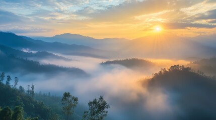 Obraz premium Morning fog blankets the hills as the sun rises over the serene mountains in a picturesque landscape