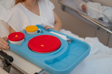 Caucasian woman eating on hospital bed. 