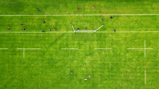 Aerial view of a rugby match on a green field. A vibrant aerial view of a rugby game in progress on a bright green field.