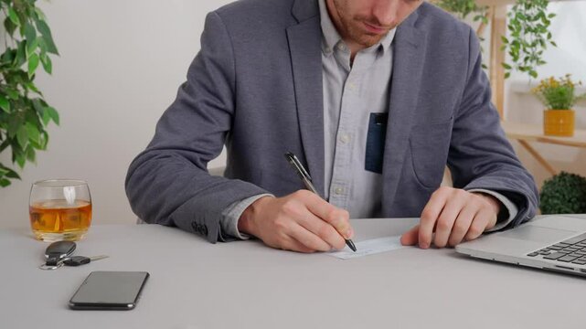 Business man sitting at office desk writing data in check book, paying or giving credit. Private commercial and business payments.