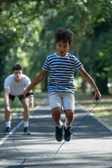 Fototapeta premium Trainer guides a child in an outdoor jump rope exercise session, focusing on improving coordination, agility, and overall fitness through fun and dynamic physical activity.