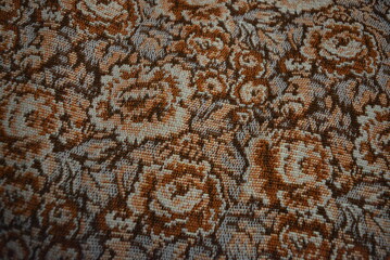 Fabric, textiles, background of threads and various floral patterns. Brown bedspreads, a blanket with small roses made of synthetic threads.
