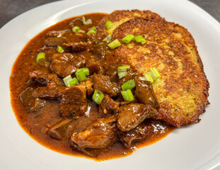 White plate with meat and oyster mushroom ragout