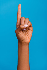Cropped vertical close up photo of woman hand finger direct up empty space isolated on blue color...