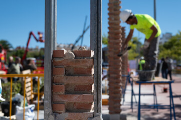 Albañil trabajando en una obra de construcción de ladrillos con paleta, nivel, ladrillos y cemento.