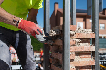 Albañil trabajando en una obra de construcción de ladrillos con paleta, nivel, ladrillos y...