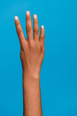 Cropped vertical close up photo of woman hand fingers count four isolated on blue color background