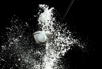 Golf Ball golfer hit snow to explode and splatter. Sand wedge golf dick ball from snow field and snow fly in air. Night black background isolated