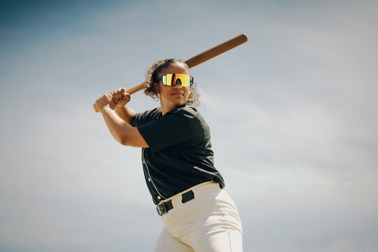Focused female baseball batter preparing to swing during a game