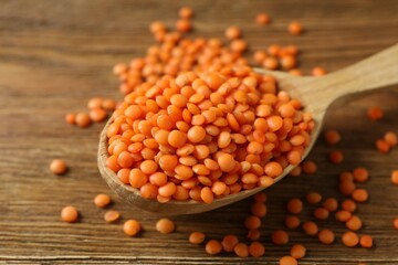 Red lentils in a spoon on wooden background 