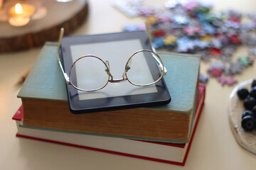 Colorful jigsaw puzzle pieces, books, tablet, glasses, cookies, berries, cup of tea or coffee, glass of juice and lit candles on the table. Hygge in pastel colors. Selective focus.