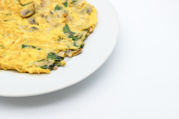 A golden omelette with mushrooms and herbs, served on a white plate against a minimalist backdrop.