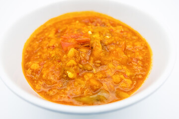 A flavorful bowl of Nam phrik ong, rich in spices and tomatoes, served in a white dish, perfect for a comforting meal.