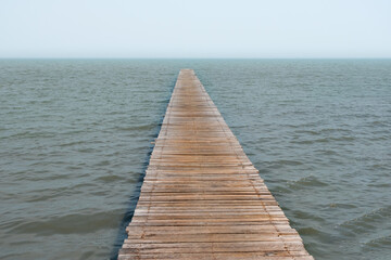 Obraz premium A wooden pier extends into calm waters, creating a serene and inviting atmosphere, perfect for contemplation and relaxation.