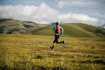 Fitness woman trail runner running in grassland