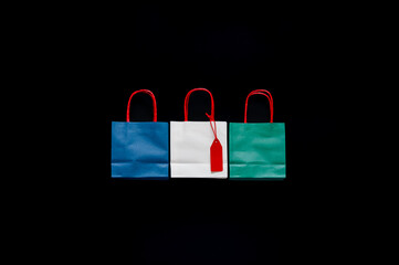 Colorful shopping bags with red price tag on white color one on black background for Black Friday shopping day concept.
