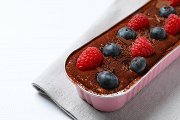 Delicious tiramisu cake with berries on table
