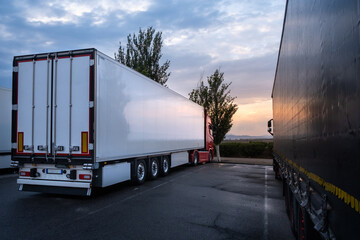 A big white truck parked at a service station at dusk to spend the night in Spain. The asphalt...