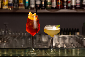 Glases of Spritz aperol and margarita cocktails, bar or pub interior, bottles with other alcohol...