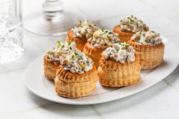 White table with creamy Chicken and Mushroom Vol Au Vent. Filled puff pastry shells, glasses with drinks. Appetizer for the festive season, mini snacks.