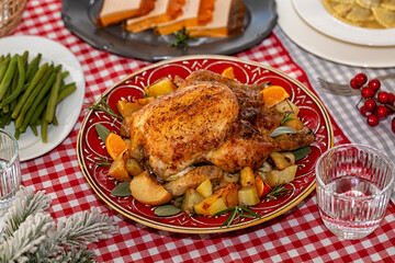 Life style Christmas or New Year feast table, central plate with roasted chicken stuffed with apples, oranges, with baked potatoes, green beans, chicken liver pate, plate of ravioli, pasta.