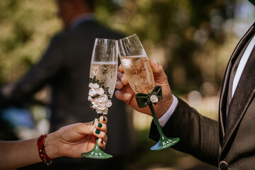Close-up of two decorated champagne glasses clinking together in a celebratory toast, each engraved...