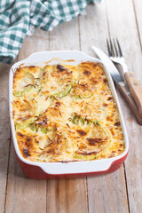 Casserole with cheese and gratin zucchini on wooden table