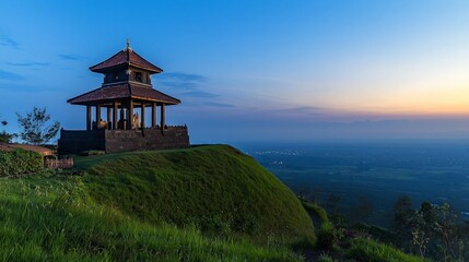 Obraz premium A traditional pavilion atop a grassy hill overlooking a valley with a city in the distance at sunset.