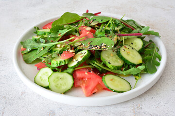 a plate of salad with cucumber, tomato and avocado and some greens