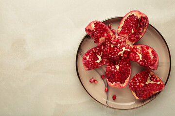 Half-cut pomegranate with seeds in plate on grey background. Top view
