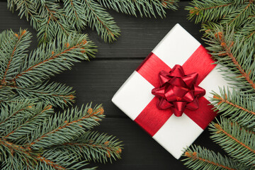 Christmas composition. Christmas gift with fir branches on black wooden background. Top view