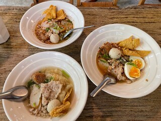 The closed up of Thai noodles with meat ball. Select and soft focus. Asian noodle soup with beef meatball with fresh vegetable on wood table.  Hot and spicy noodle soup, Asian food.