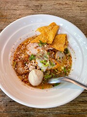 The closed up of Thai noodles with meat ball. Select and soft focus. Asian noodle soup with beef meatball with fresh vegetable on wood table.  Hot and spicy noodle soup, Asian food.