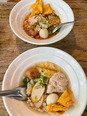 The closed up of Thai noodles with meat ball. Select and soft focus. Asian noodle soup with beef meatball with fresh vegetable on wood table.  Hot and spicy noodle soup, Asian food.