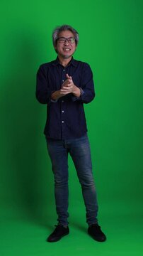 The senior Asian man standing on the green screen background.