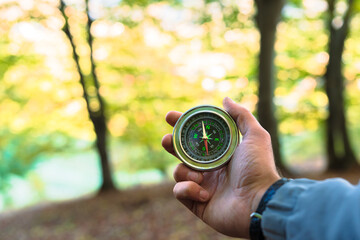 Naklejka premium Compass in man's hands, autumn forest, travel
