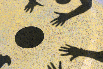 shadows of hands and ball on the floor of a basketball court photographed during a match at the moment of shooting the basket