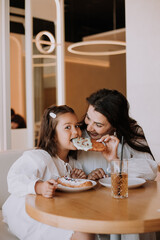 mom and daughter have breakfast in a cafe
